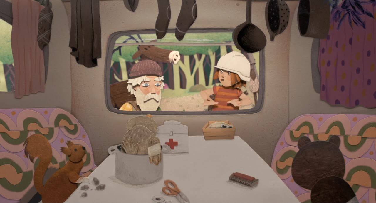 Blick aus dem Wohnwagen durch das Fenster auf Lucie und den Zauberer. Im Inneren des Wohnwagens sind Verbände, Medizin und einige Tiere zu sehen.