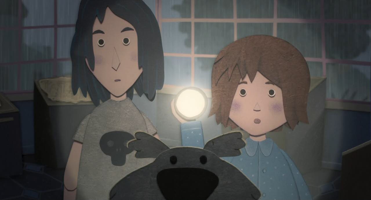 Lucie, Yann und der Hund Mandrin sind im Museum und schauen auf eine Wand, an der Bilder hängen. Lucie hat eine Taschenlampe in der Hand, die die Betrachter*innen direkt anstrahlt.