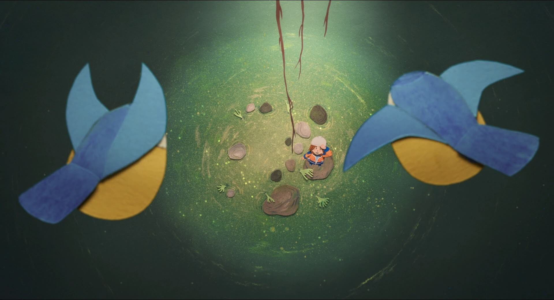 Blick von der Höhe der beiden Blaumeisen auf Lucie die auf dem wasserbedeckten Boden der Höhle steht und zu den Blaumeisen heraufschaut.