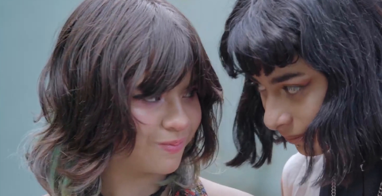 Nahaufnahme von Valentina und Karla, die sich lächelnd ansehen. Beide tragen ihre schulterlangen Haare offen und sind dezent geschminkt.