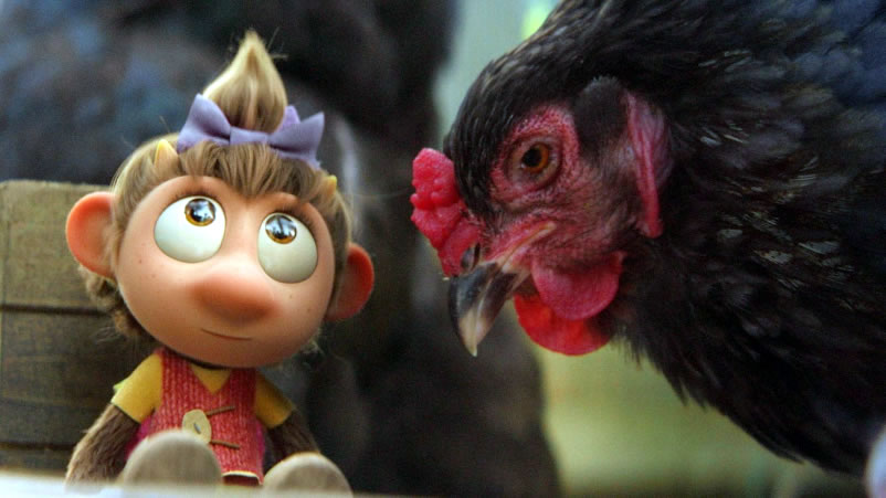 Filmbild: Bonny sitzt starr, während ein Huhn ihr sehr nah kommt.