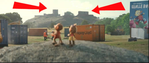 Filmbild: Billy und Bonny stehen auf einem Fels und schauen über eine Baustelle. Im Hintergrund ist eine Burg zu sehen, die mit Pfeilen markiert ist.